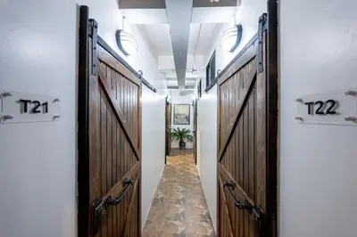 a hallway with wooden doors and a hallway with a plant at Vibes Hostel Bangkok in Bangkok