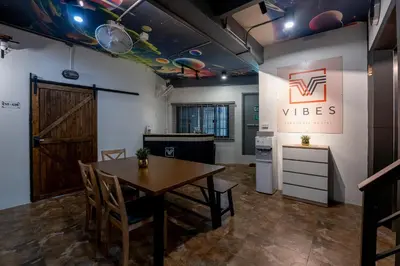 a room with a table and chairs and a kitchen at Vibes Hostel Bangkok in Bangkok