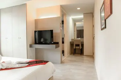 a room with a bed and a tv on a wall at Shine Sukhumvit 33 Aparthotel Phrompong in Bangkok