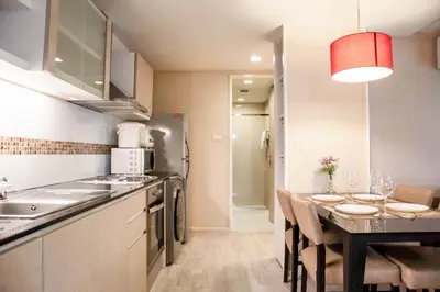 a kitchen with a table and a dining room at Shine Sukhumvit 33 Aparthotel Phrompong in Bangkok