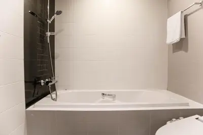 a white bath tub in a bathroom with a toilet at Shine Sukhumvit 33 Aparthotel Phrompong in Bangkok
