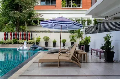 a pool with chairs and an umbrella and a pool at Shine Sukhumvit 33 Aparthotel Phrompong in Bangkok