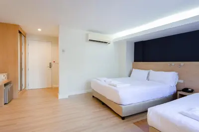 a hotel room with two beds and a large white bed at GP House Express Sukhumvit 81 in Bangkok