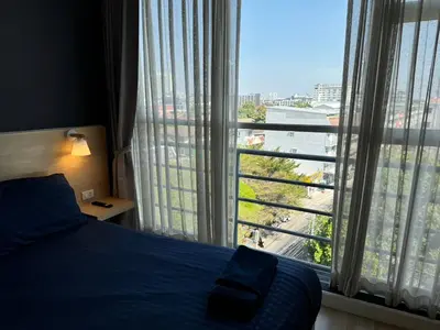 a bedroom with a bed and a large window at GP House Express Sukhumvit 81 in Bangkok
