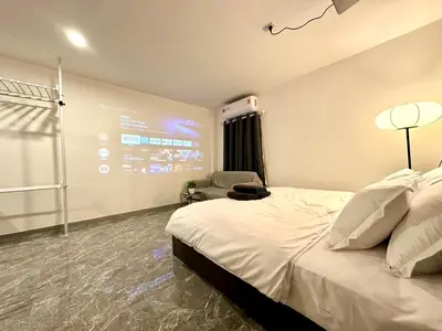 a hotel room with a bed and a chair at The White Den Chatuchak in Bang O