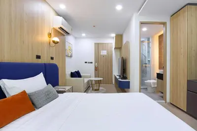 a bedroom with a large white bed and a bathroom at Aquila Hotel Bangkok in Bangkok