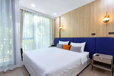 a bedroom with a large bed with a blue wall at Aquila Hotel Bangkok in Bangkok