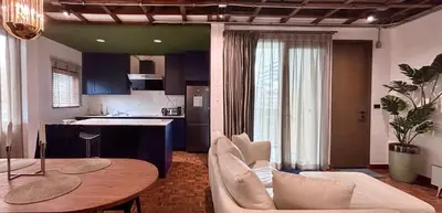 a living room with a table and a kitchen at Brown Brick Thonglor - Green Greenery Room in Bangkok