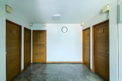 a hallway with wooden doors and a clock on a wall at XX GO INN Khaosan The Grand Palace Bangkok in Bangkok