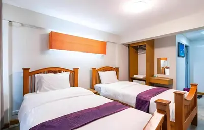 a bedroom with two beds and a mirror at XX GO INN Khaosan The Grand Palace Bangkok in Bangkok