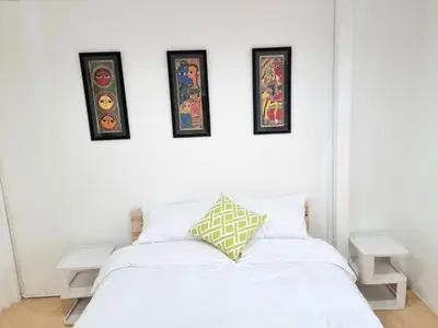 a bedroom with a white bed with four pictures on the wall at Haus Sathorn Pier 2 Cozy Bedroom City Center in Bangkok