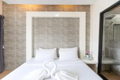 two white swans sitting on a bed in a bedroom at Baron Zotel Bangkok SHA PLUS in Bangkok