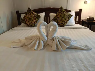 two swansrendered to look like they are kissing on a bed at Baan Debtida in Bangkok