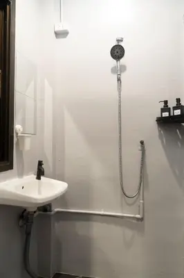 a white bathroom with a shower and a sink at Round The Clock Hostel in Samphanthawong