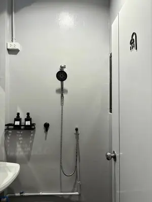 a white bathroom with a shower and a sink at Round The Clock Hostel in Samphanthawong