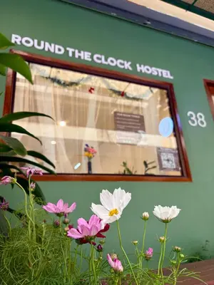 a window of a store with flowers in front of it at Round The Clock Hostel in Samphanthawong