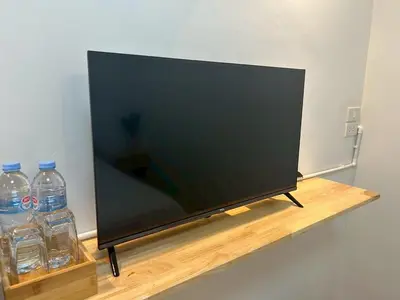 a flat screen tv sitting on a shelf with two water bottles at Choose me guesthouse in Bang Kruai