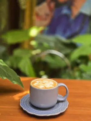a cup of coffee on a saucer on a table at Vonden Garden by Merry V in Bangkok