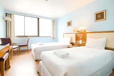 a hotel room with two beds and a desk at XX Wish Inn BTS Chidlom - วิช อินน์ บีทีเอส ชิดลม in Pratunam