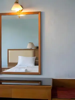 a mirror on a dresser next to a bed at XX Wish Inn BTS Chidlom - วิช อินน์ บีทีเอส ชิดลม in Pratunam