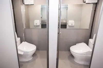 a bathroom with two toilets and two mirrors at DMK Place in Bangkok