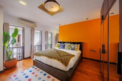 a bedroom with a bed with an orange wall at \u83f2\u65af\u4e4b\u57ce\u66fc\u8c371200\u5e73\u7687\u5bb6\u68ee\u7cfb\u6cf3\u6c60\u6d3e\u5bf9\u522b\u5885 in Bangkok