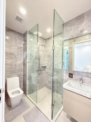 a bathroom with a shower and a toilet and a sink at Brand New Condo in Bangkok
