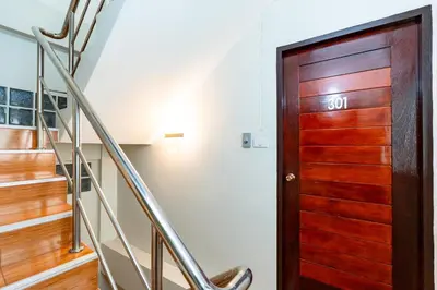 a wooden door in a hallway with stairs at The Hidden Giant Swing เดอะ ฮิดเด้น เสาชิงช้า in Bangkok