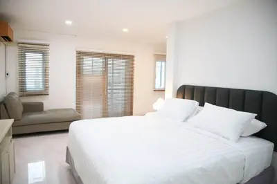 a bedroom with a large white bed and a couch at Near BTS Bearing Skytrain- Homey living Townhome - 4 Bedrooms in Bangkok