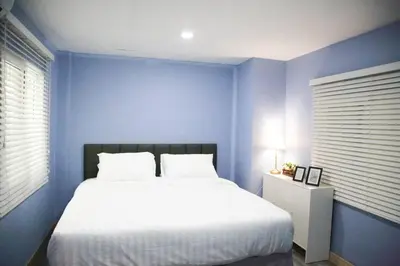 a blue bedroom with a white bed and a blue wall at Near BTS Bearing Skytrain- Homey living Townhome - 4 Bedrooms in Bangkok