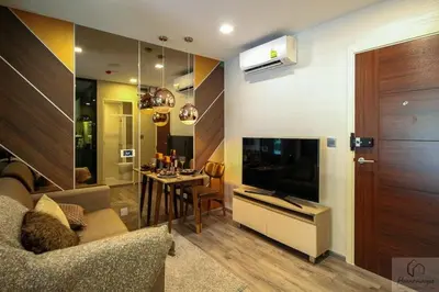 a living room with a couch and a television and a table at brown condo Phahon67 in Ban Chuat Plai Mai