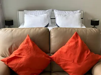 a brown couch with two red pillows on it at King Bed Studio in Bangkok