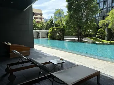 a chair and a table next to a swimming pool at King Bed Studio in Bangkok