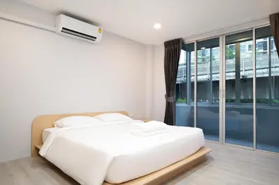 a white bed in a room with a window at Wash House Chatuchak in Bangkok