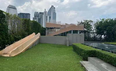 a building with a bench in a field of grass at Luxury condo right next to BTS Thonglor! in Bangkok