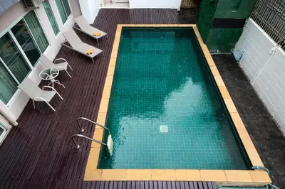an empty swimming pool on a deck with chairs at Story At Bangkok- 211 Studio with Balcony in Khlong Toei