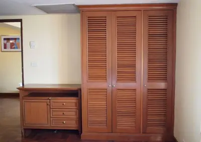 a wooden closet with a dresser and a mirror at Spacious room in Sukhumvit Nana in Bangkok