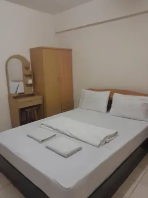 a bedroom with a bed with white sheets and a mirror at Nakara Place บ้าน นาครา in Ban Rang Pho