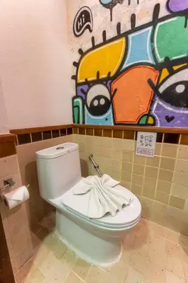 a bathroom with a toilet with a painting on the wall at Mak Sukhumvit 15 in Bangkok