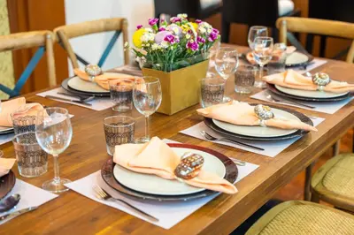 a long wooden table with plates and glasses and flowers at Mak Sukhumvit 15 in Bangkok