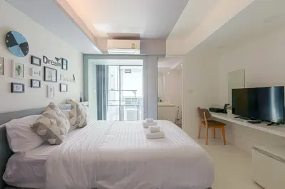 a white bedroom with a large bed and a television at Quite Grove Hotel in Bangkok