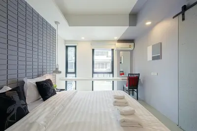 a bedroom with a large white bed and a chair at Quite Grove Hotel in Bangkok