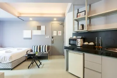 a bedroom with a bed and a kitchen with a microwave at Quite Grove Hotel in Bangkok