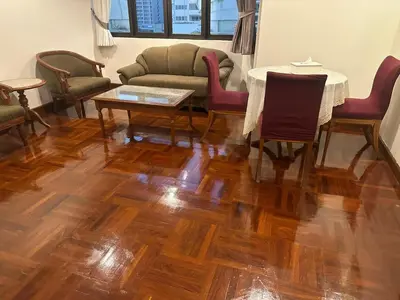 a living room with wooden floors and a table and chairs at Spacious 1,2 & 3 Bedroom Serviced Apartments OMNI - Nana BTS in Bangkok