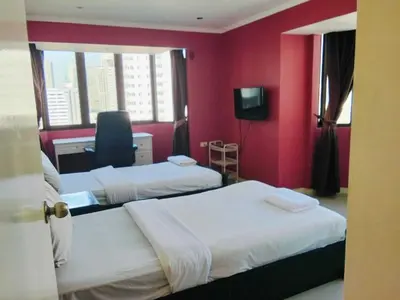 two beds in a room with red walls and a chair at Spacious 1,2 & 3 Bedroom Serviced Apartments OMNI - Nana BTS in Bangkok