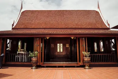 a building with a wooden door with two potted plants at เรือนไทยพราวพิมาน Proudpiman Thai Heritage House in Ban Bang Toei (1)
