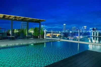 a swimming pool on the roof of a building at night at Cosy apartment - BTS Phrom phong in Bangkok