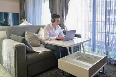 a man wearing headphones sitting on a couch with a laptop at Cosy apartment - BTS Phrom phong in Bangkok