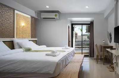 a bedroom with two beds and a table and a desk at bang khun thian14 in Sathani Wat Sing