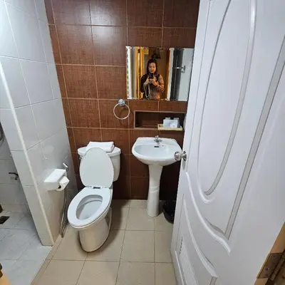 a woman taking a picture of a bathroom with a toilet and sink at bang khun thian14 in Sathani Wat Sing
